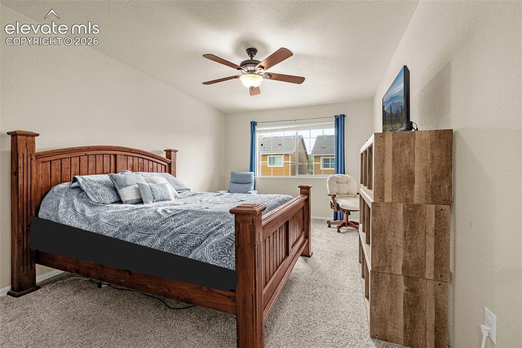 Image 13 of 38: Carpeted Primary Bedroom featuring a wooden ceiling fan with integrated lig
