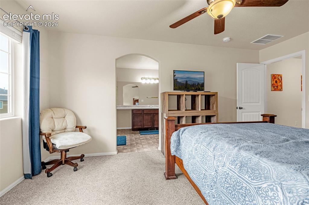 Image 14 of 38: Primary bedroom with neutral carpet flooring and a ceiling fan light fixtur