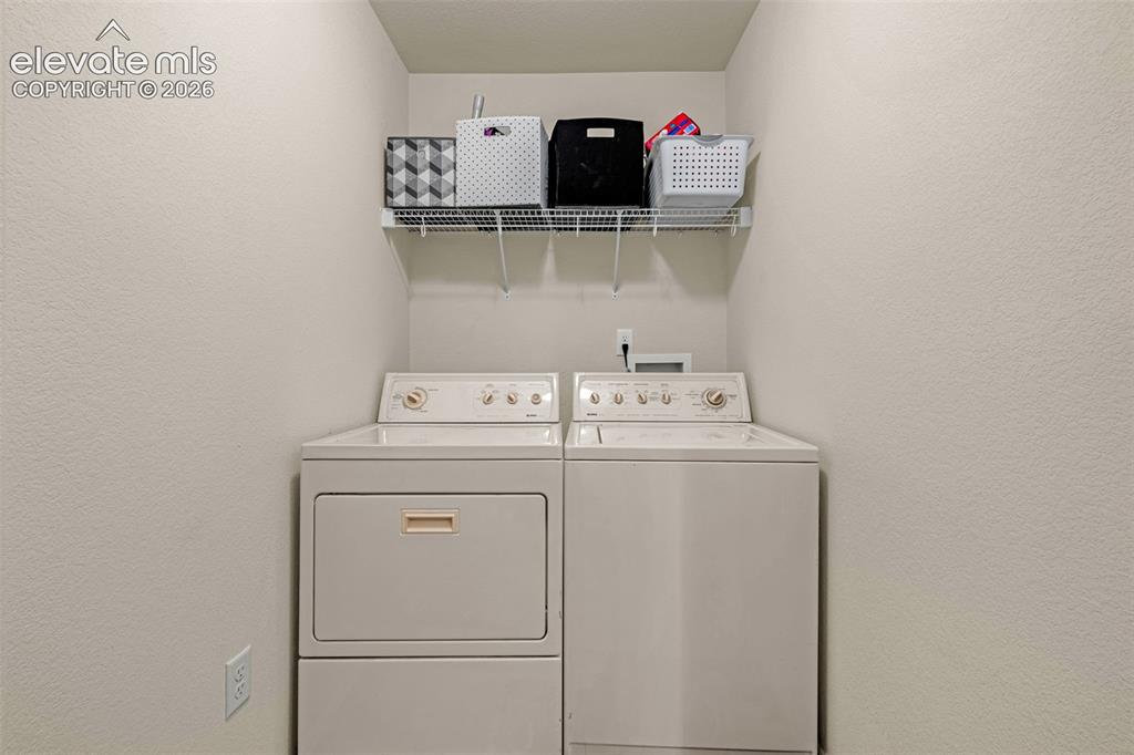 Image 24 of 38: Dedicated laundry area featuring a white top-load washing machine, a white
