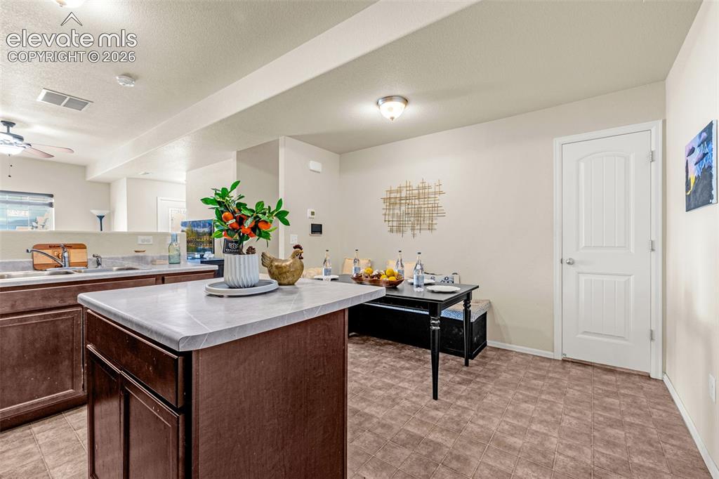 Image 4 of 38: Kitchen island featuring a countertop, dark wood-finish cabinetry, and a ti