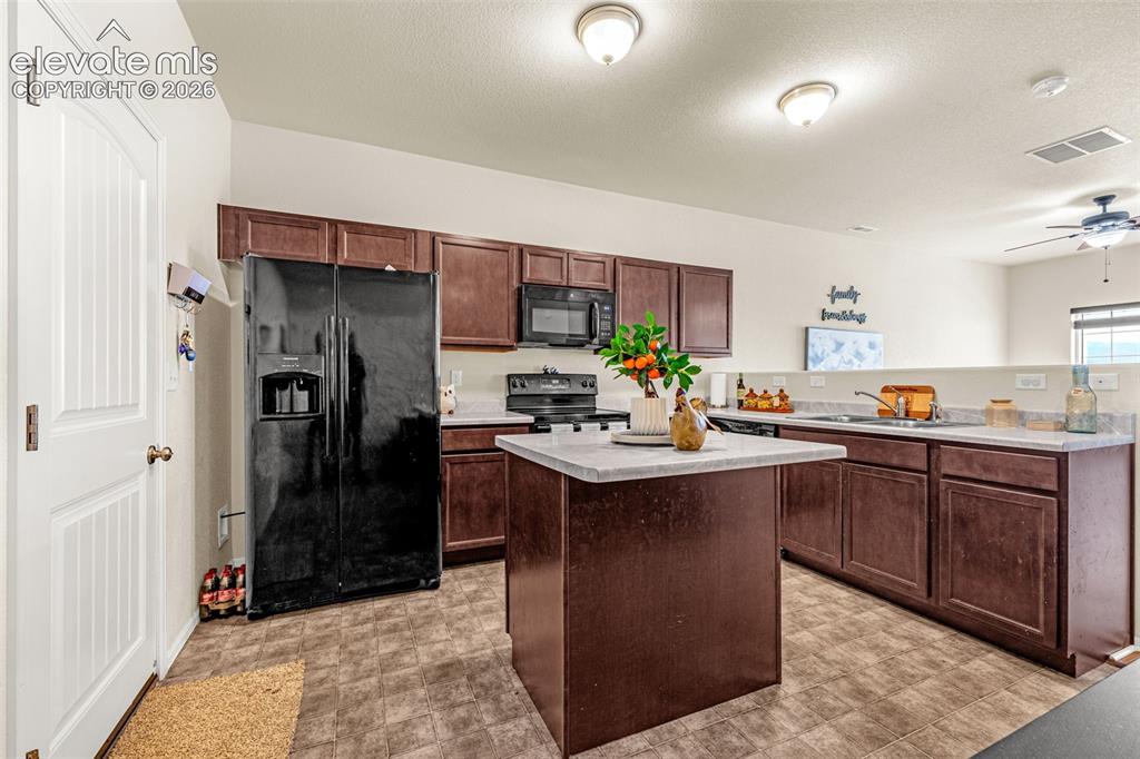 Image 5 of 38: Kitchen featuring dark wood-finish cabinetry, solid surface countertops, an