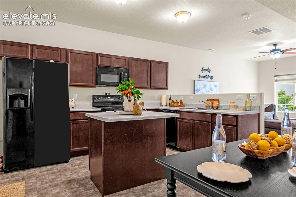 Image 6 of 38: Kitchen featuring dark wood-finish cabinetry, light stone-finish countertop