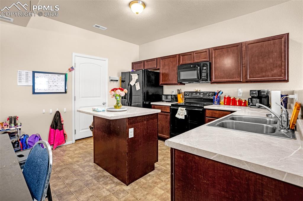 Image 8 of 30: Kitchen featuring black appliances, light countertops, a kitchen island, an