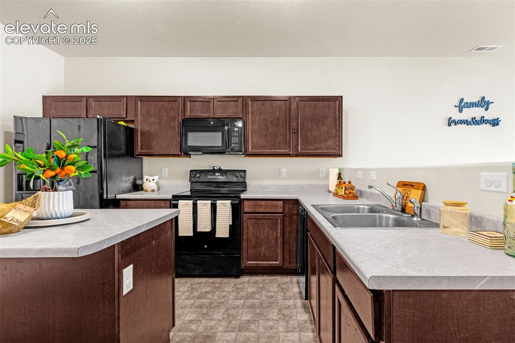 Image 8 of 38: Kitchen featuring dark wood-finish cabinetry, black appliances, light-toned