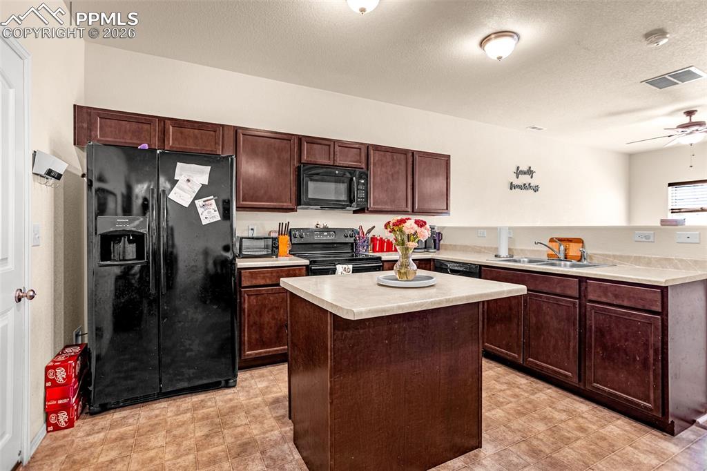 Image 9 of 30: Kitchen with black appliances, light countertops, ceiling fan, a textured c