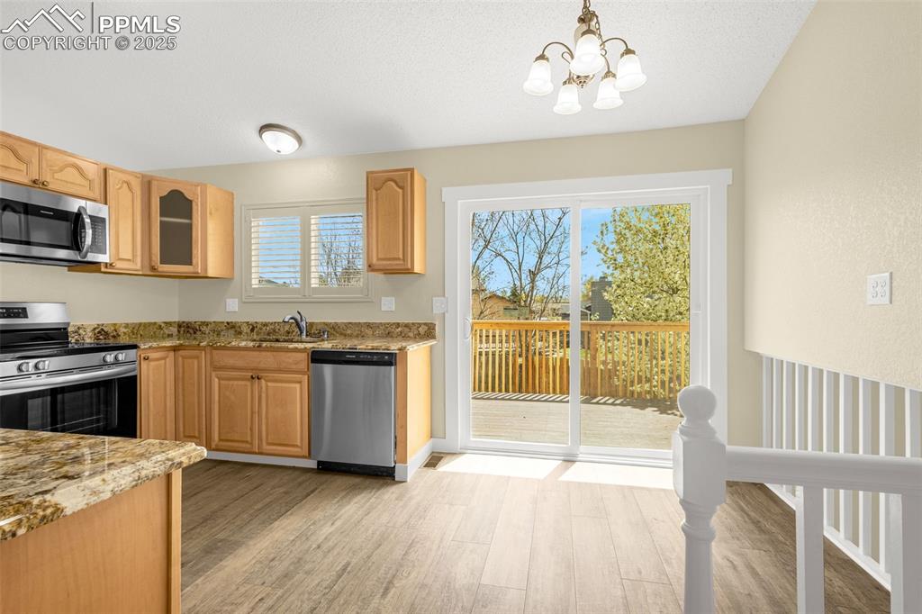 Image 10 of 36: Kitchen with light stone countertops, an inviting chandelier, stainless ste