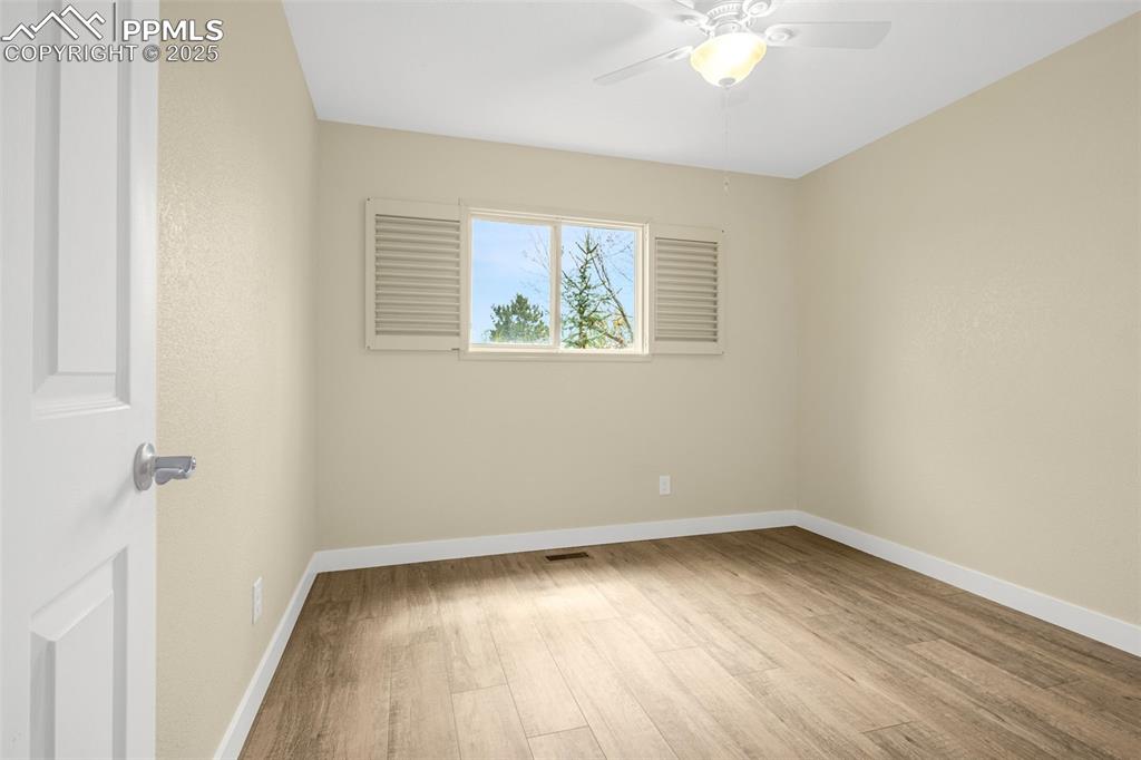 Image 13 of 36: Spare room featuring wood finished floors, ceiling fan, visible vents, and 