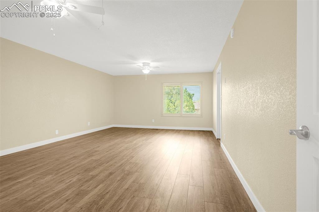 Image 14 of 36: Empty room with a ceiling fan, wood finished floors, and baseboards