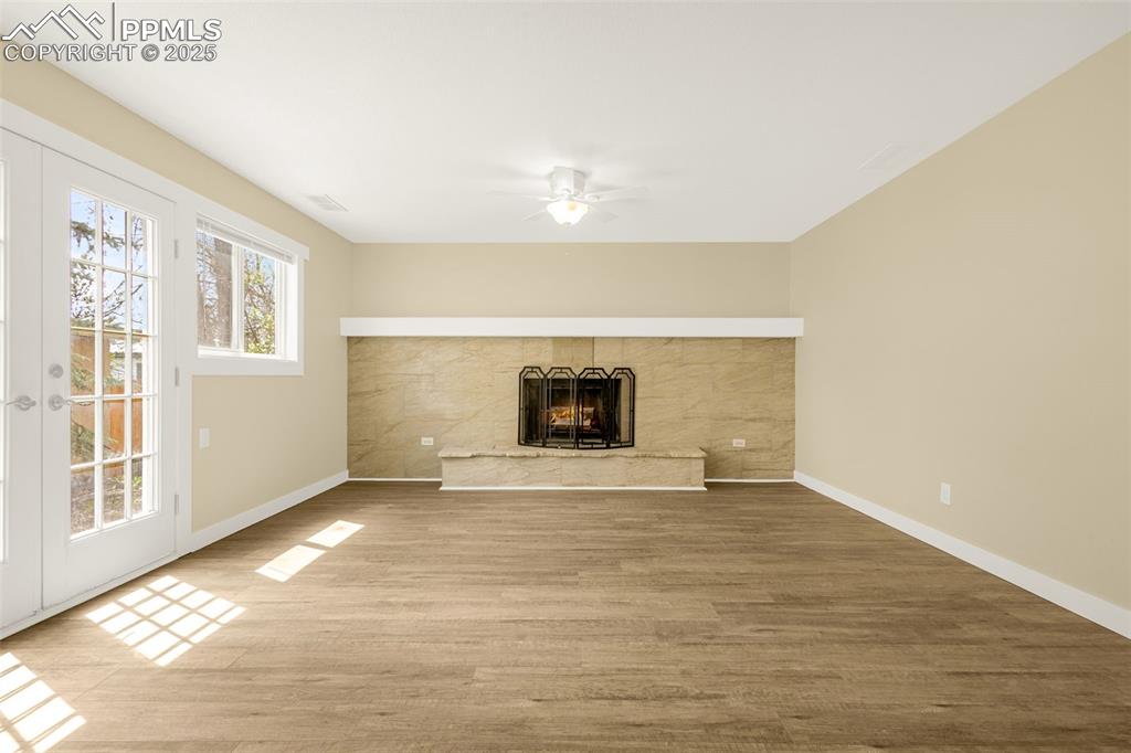 Image 21 of 36: Unfurnished living room featuring wood finished floors, a ceiling fan, a li