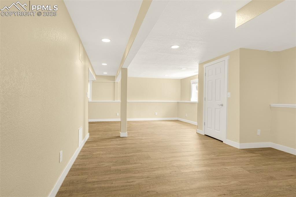 Image 25 of 36: Below grade area with light wood-style flooring and baseboards