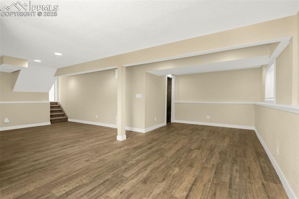 Image 27 of 36: Below grade area with stairway, wood finished floors, recessed lighting, an