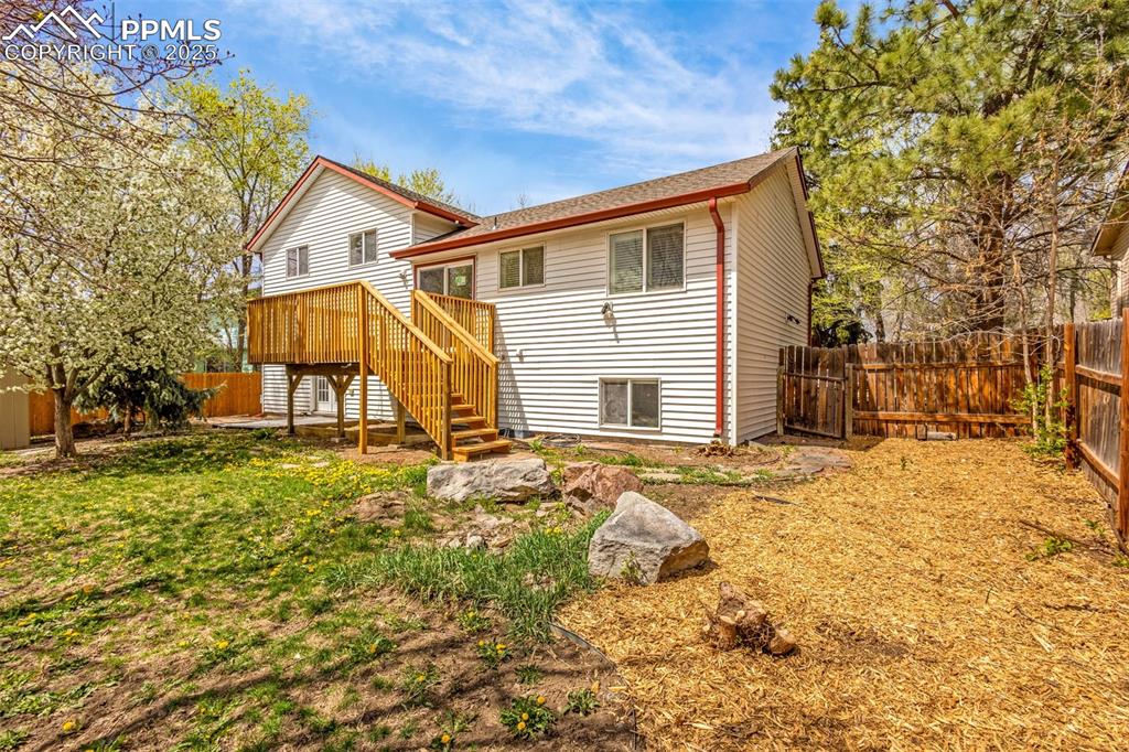 Image 32 of 36: Back of property with stairway, a deck, a shingled roof, and a fenced backy