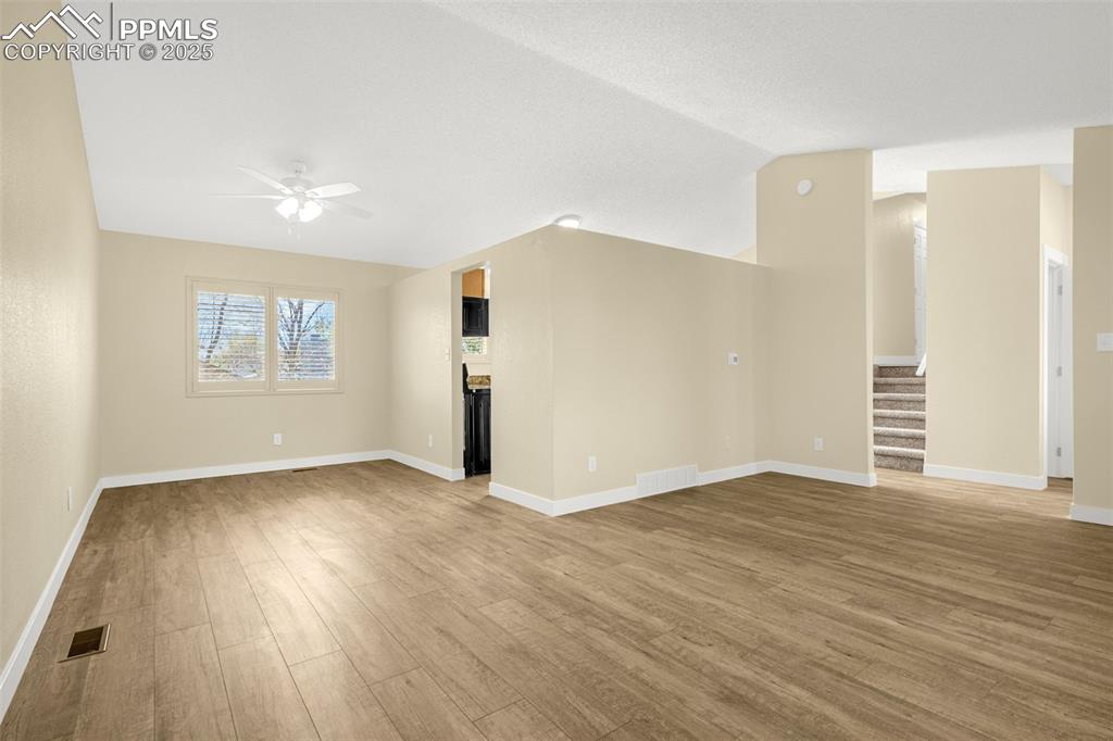 Image 6 of 36: Unfurnished living room with a ceiling fan, visible vents, wood finished fl