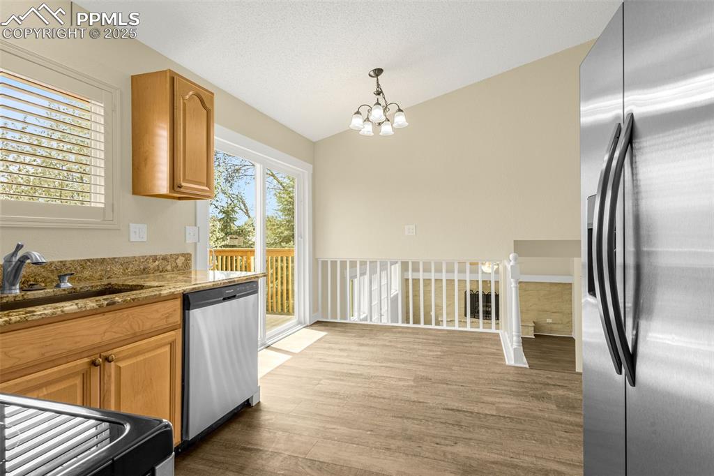 Image 9 of 36: Kitchen with lofted ceiling, wood finished floors, stainless steel applianc