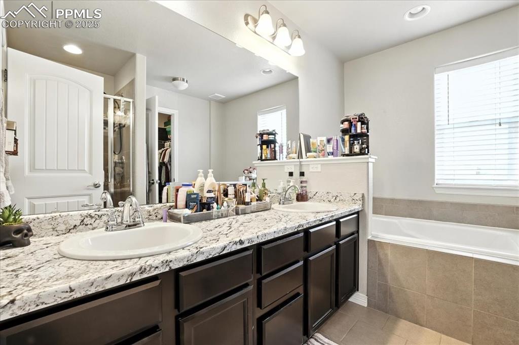 Image 17 of 31: Bathroom with a spacious closet, double vanity, a stall shower, recessed li