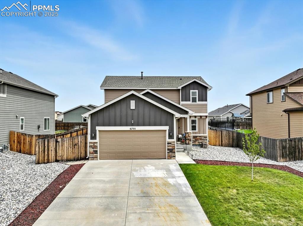 Image 2 of 31: View of front of home with board and batten siding, stone siding, a garage,