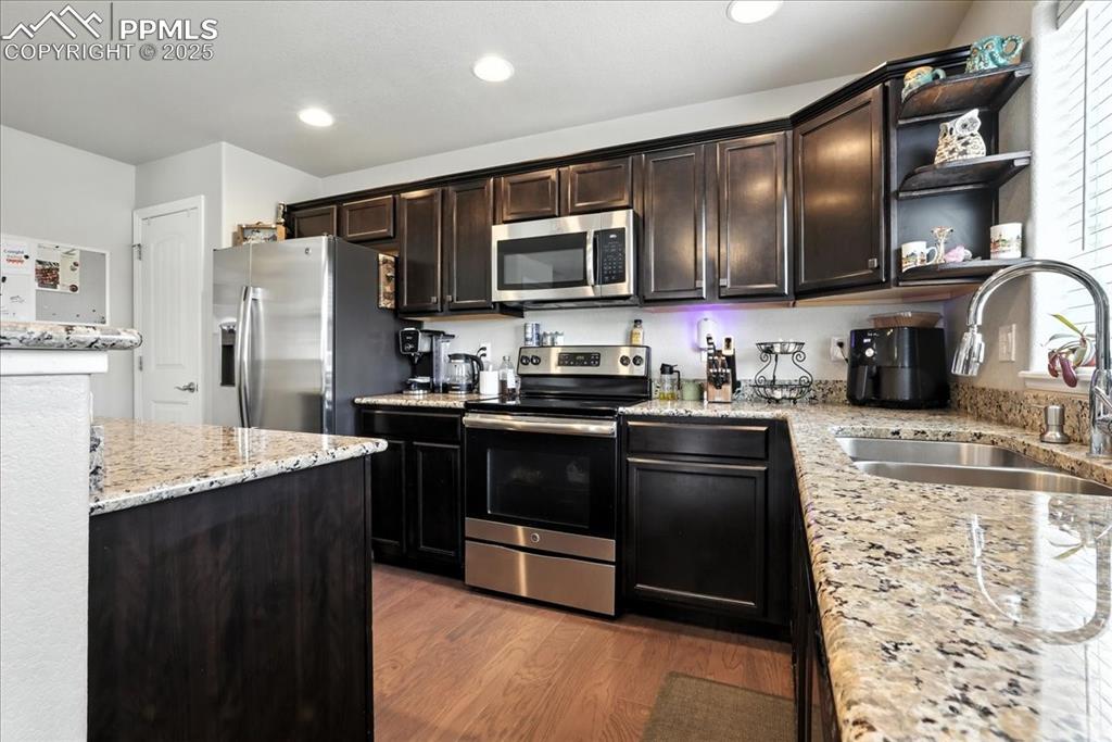 Image 22 of 31: Kitchen with light stone counters, stainless steel appliances, open shelves