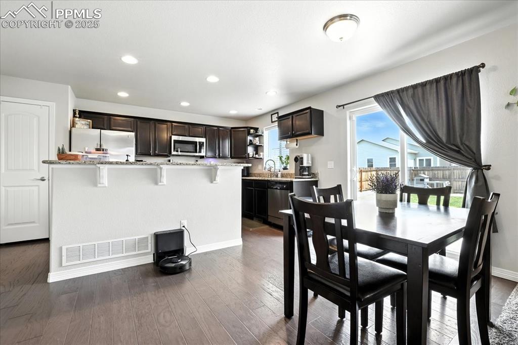 Image 7 of 31: Dining room featuring dark wood finished floors and recessed lighting