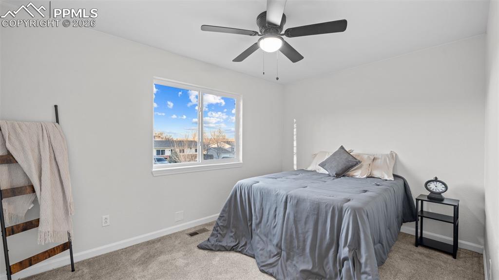 Image 13 of 38: Bedroom with light colored carpet and a ceiling fan