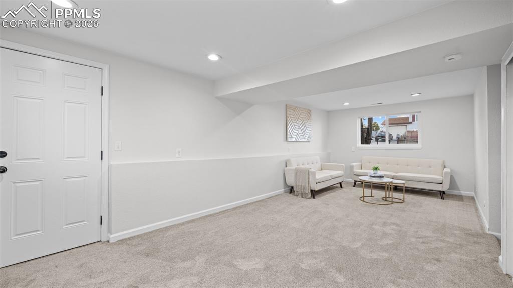 Image 21 of 38: Sitting room with light colored carpet and recessed lighting