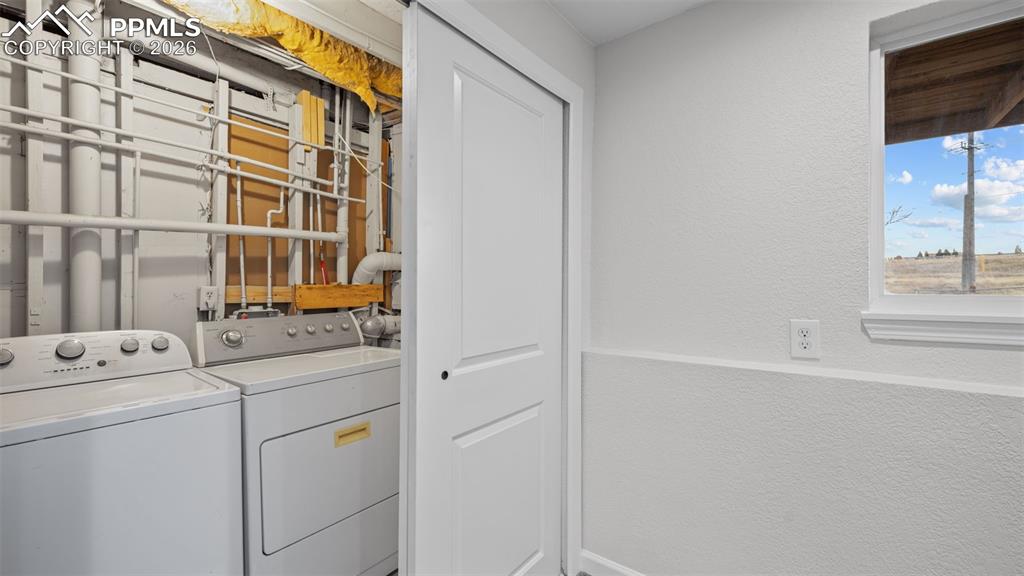 Image 24 of 38: Laundry area featuring a textured wall and washing machine and clothes drye