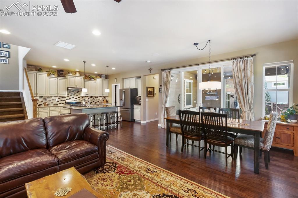 Image 13 of 50: Living room featuring dark wood-type flooring, a ceiling fan, stairway, and