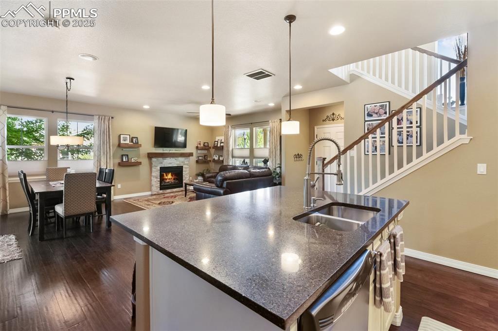 Image 17 of 50: Kitchen featuring dishwasher, a stone fireplace, dark wood-type flooring, a