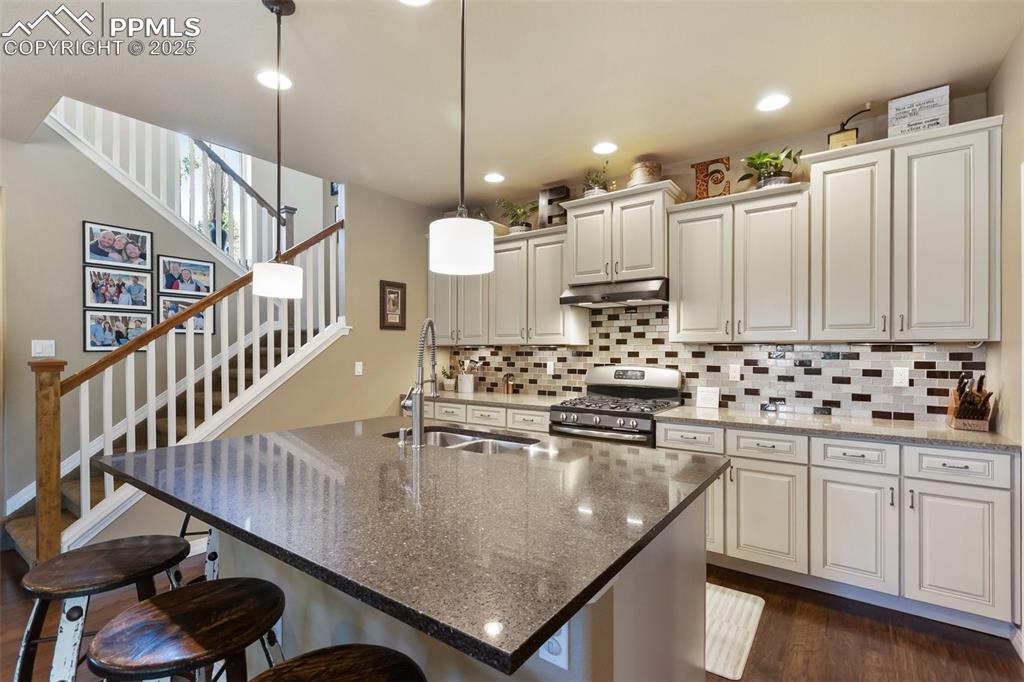 Image 20 of 50: Kitchen with stainless steel gas range oven, under cabinet range hood, tast