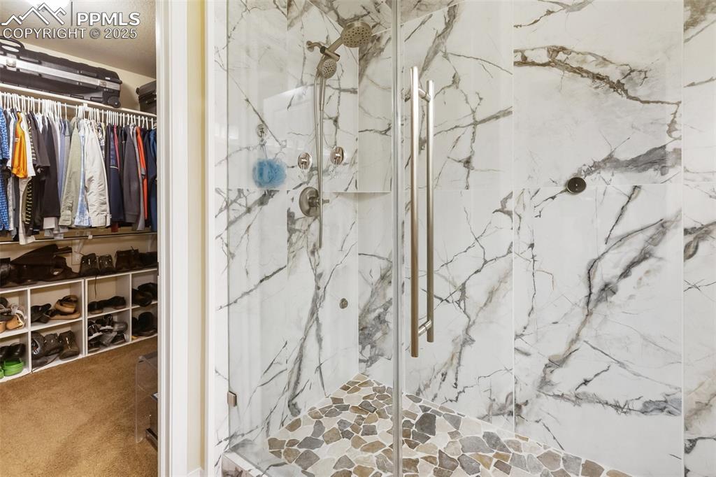 Image 22 of 50: Bathroom with a marble finish shower and a walk in closet