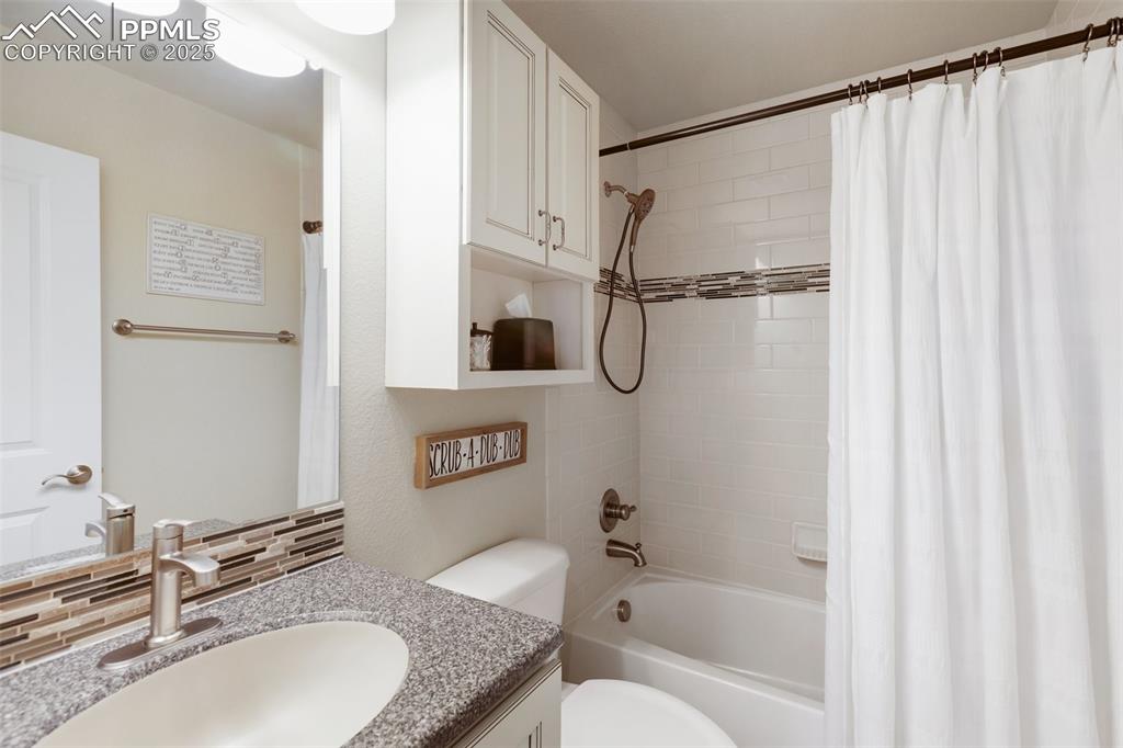 Image 31 of 50: Bathroom with vanity, shower / tub combo with curtain, and decorative backs