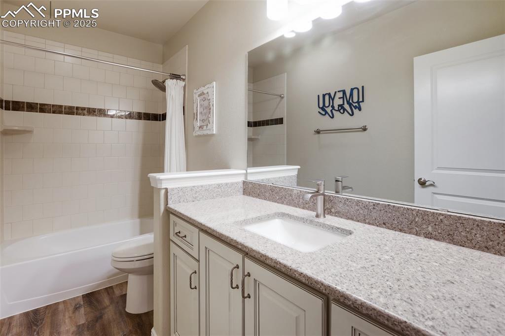 Image 38 of 50: Bathroom with vanity, shower / bath combo, and wood finished floors