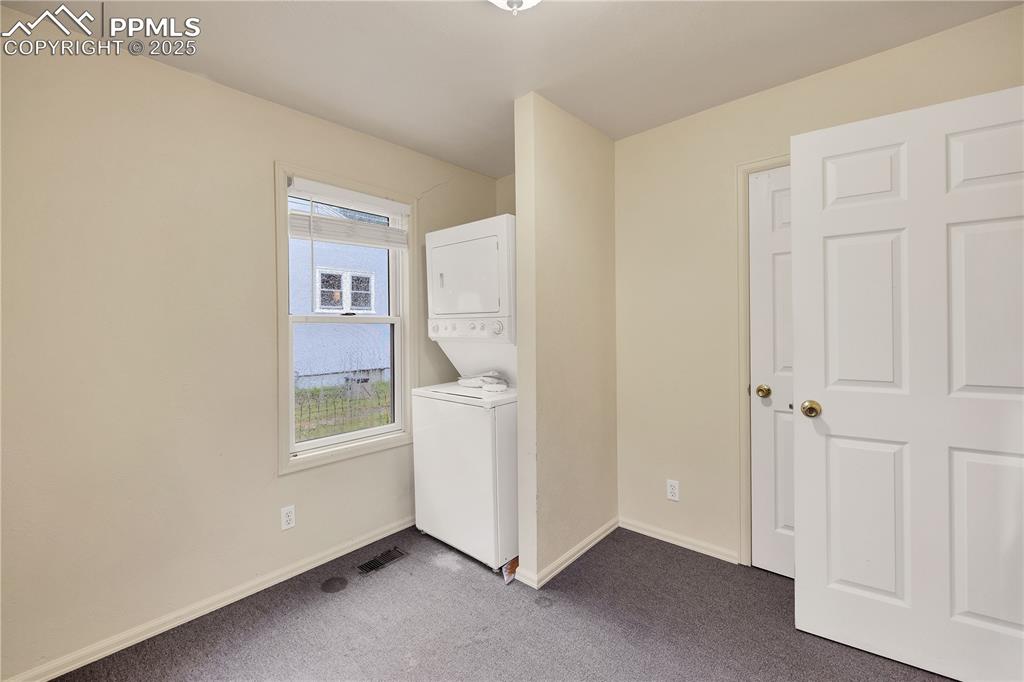 Image 16 of 16: Washroom featuring carpet and stacked washer / drying machine