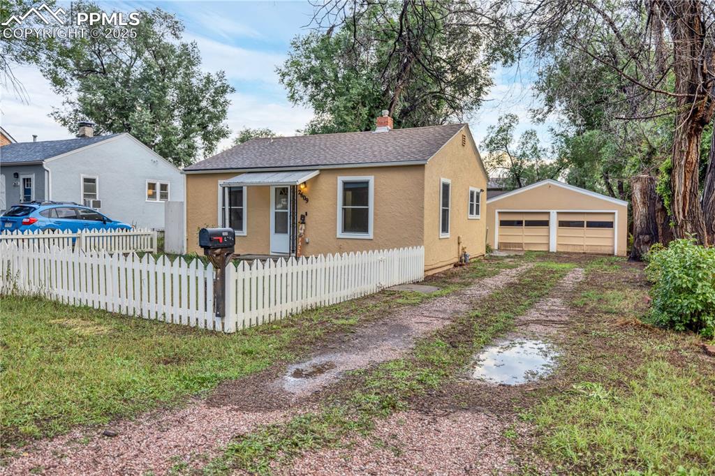 Image 2 of 16: Bungalow-style house featuring stucco siding, a detached garage, an outbuil