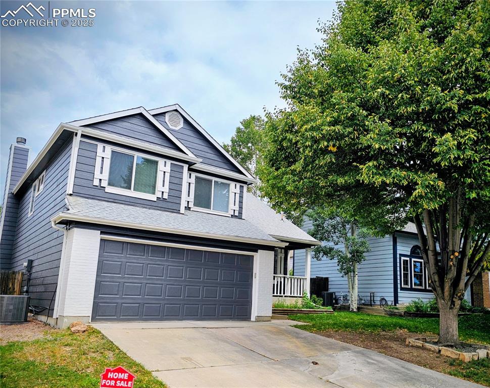 Caption: Traditional-style house with an attached garage, concrete driveway, and brick siding
