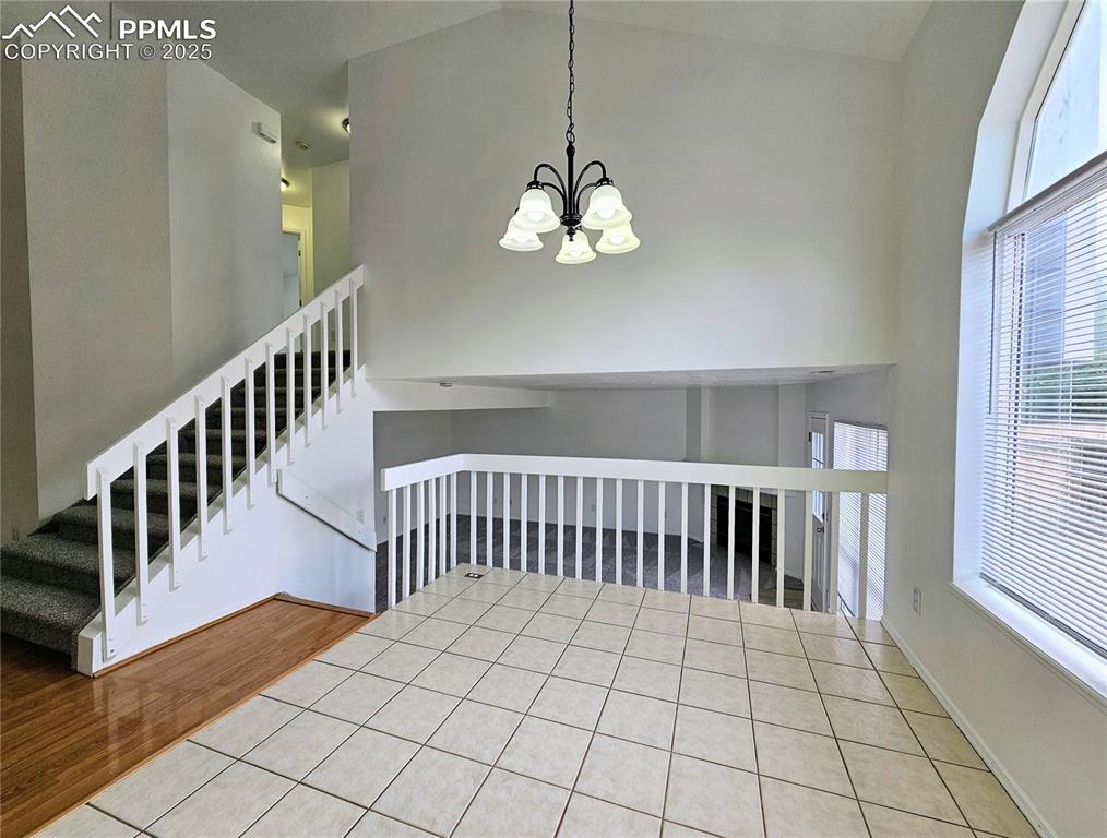 Image 13 of 31: Unfurnished dining area with tile patterned floors, a chandelier, a high ce