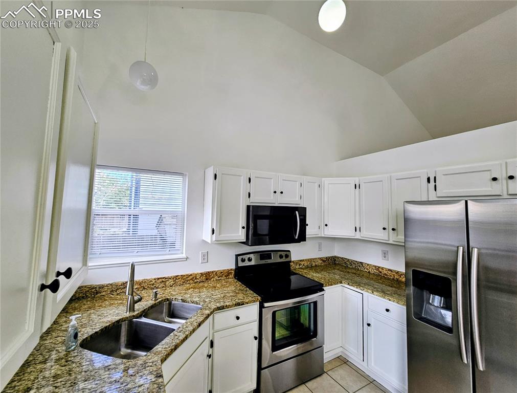 Image 14 of 31: Kitchen with appliances with stainless steel finishes, white cabinetry, dar
