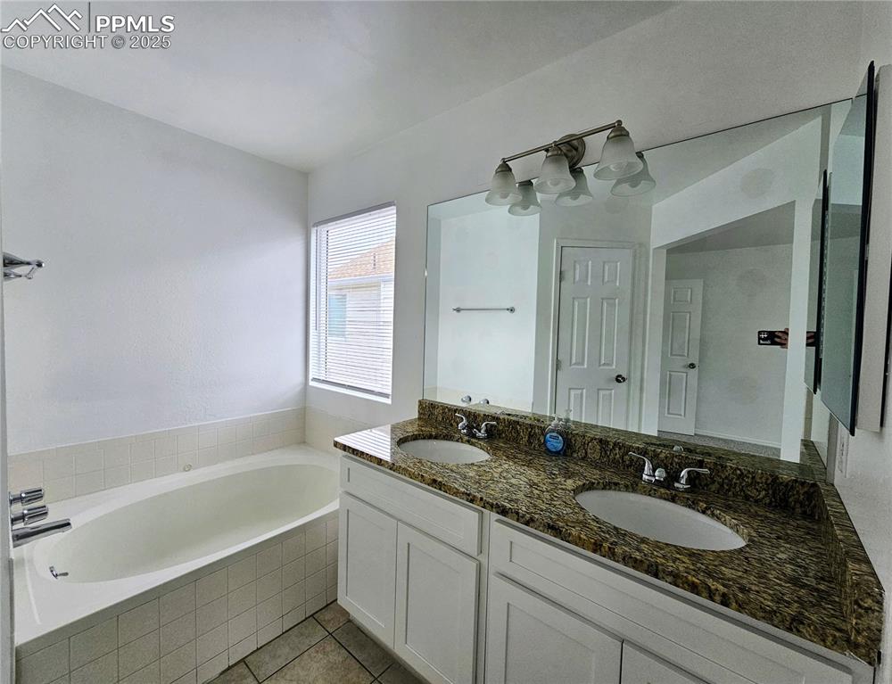Image 17 of 31: Full bath featuring a bath, double vanity, and light tile patterned floorin