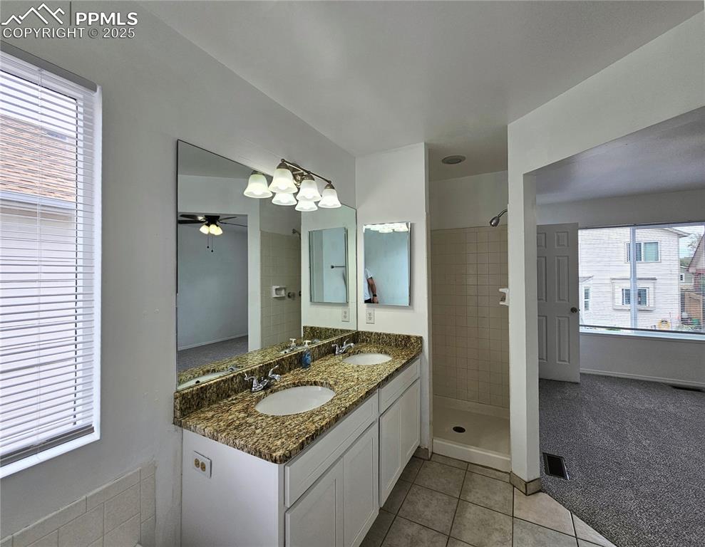 Image 19 of 31: Bathroom with double vanity, light tile patterned floors, a shower stall, a