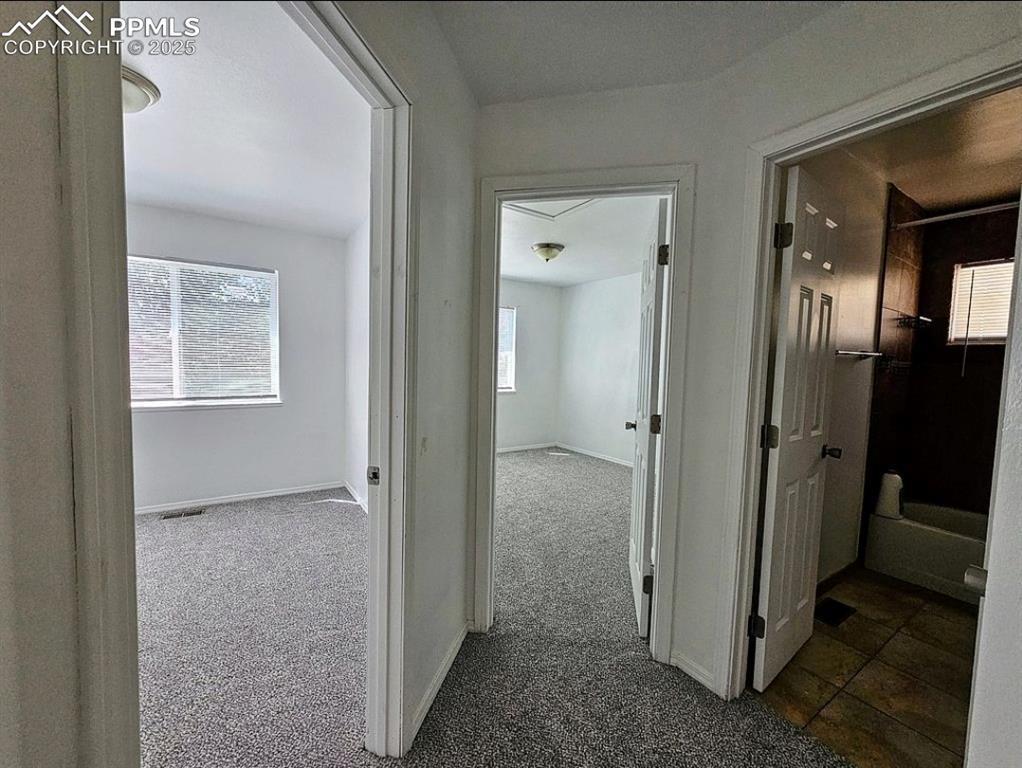 Image 20 of 31: Hallway with dark carpet and baseboards