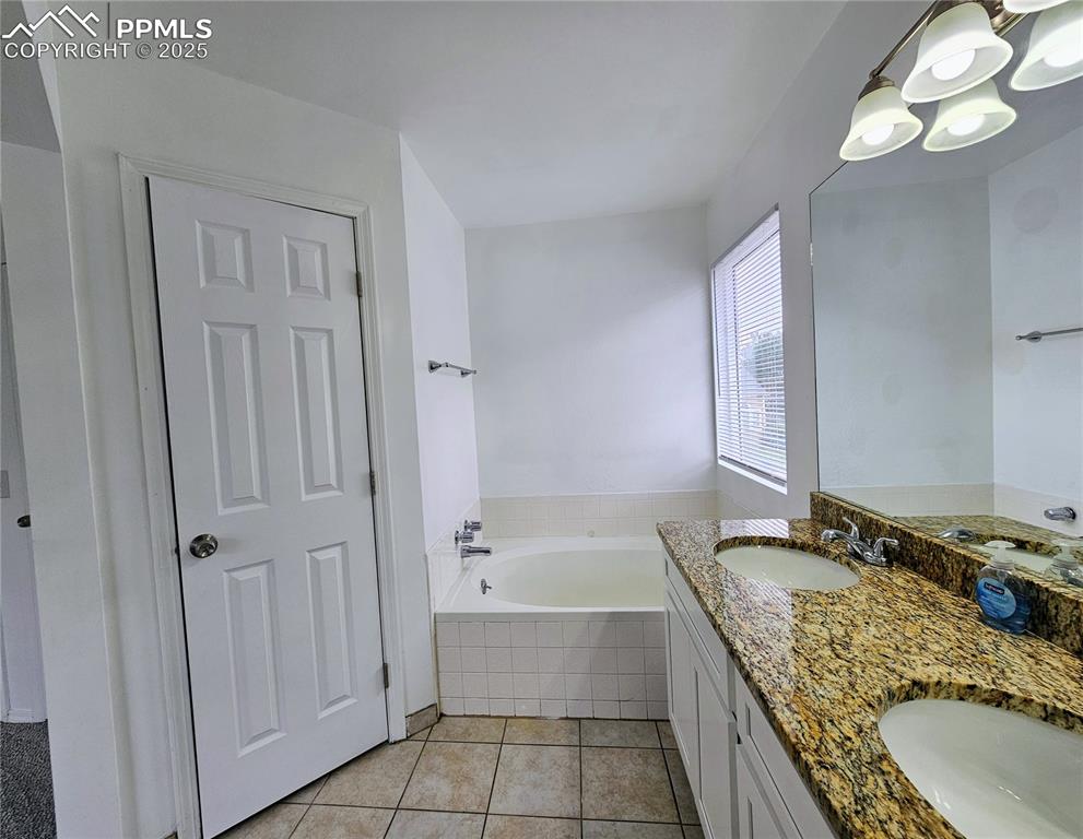 Image 21 of 31: Full bathroom featuring a bath, light tile patterned floors, double vanity,