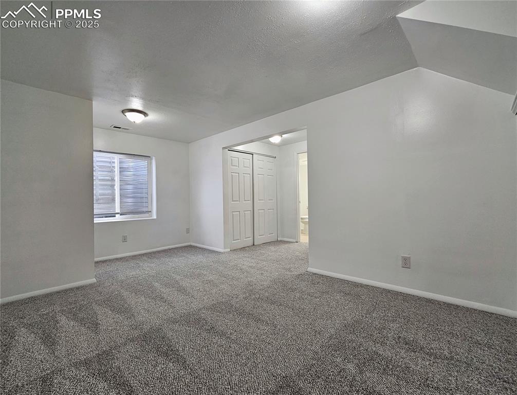 Image 26 of 31: Carpeted spare room with a textured ceiling and baseboards