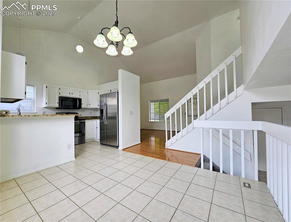 Image 7 of 31: Kitchen featuring white cabinetry, stainless steel appliances, a chandelier