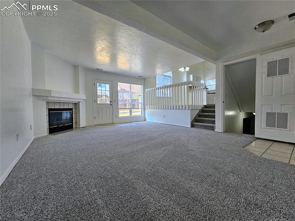 Image 9 of 31: Unfurnished living room featuring light carpet, stairs, a textured ceiling,