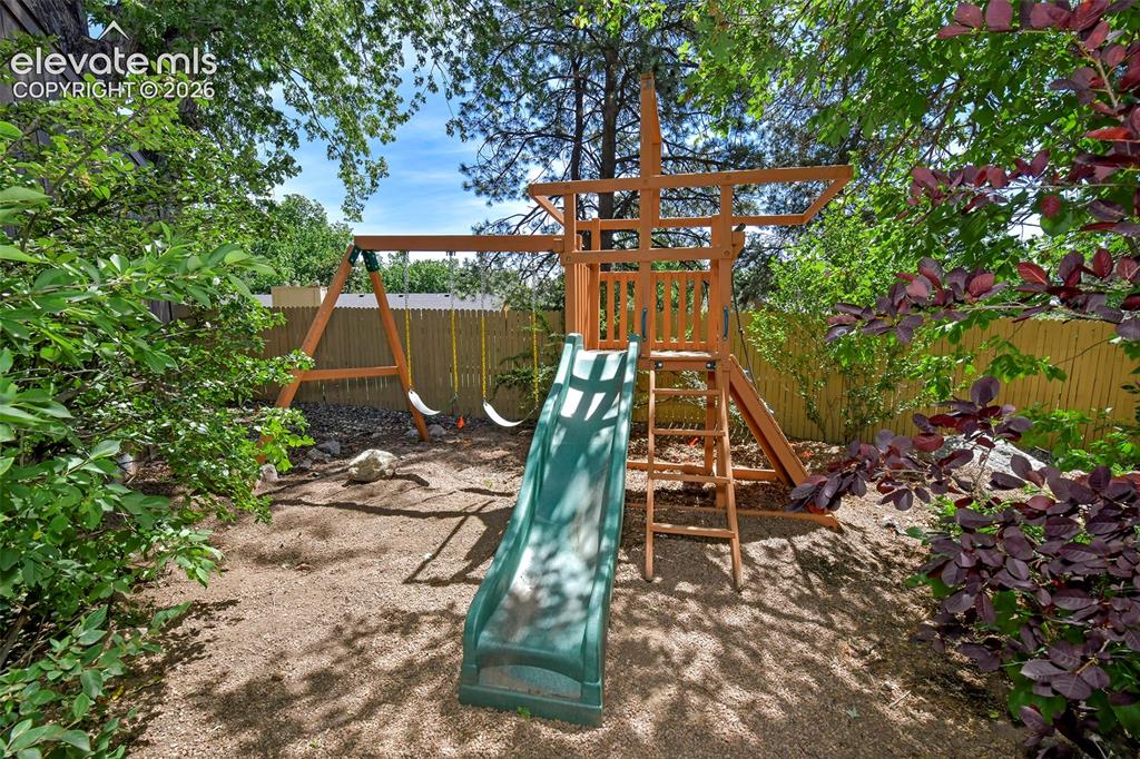 Image 37 of 50: Hidden playset in corner of fenced yard