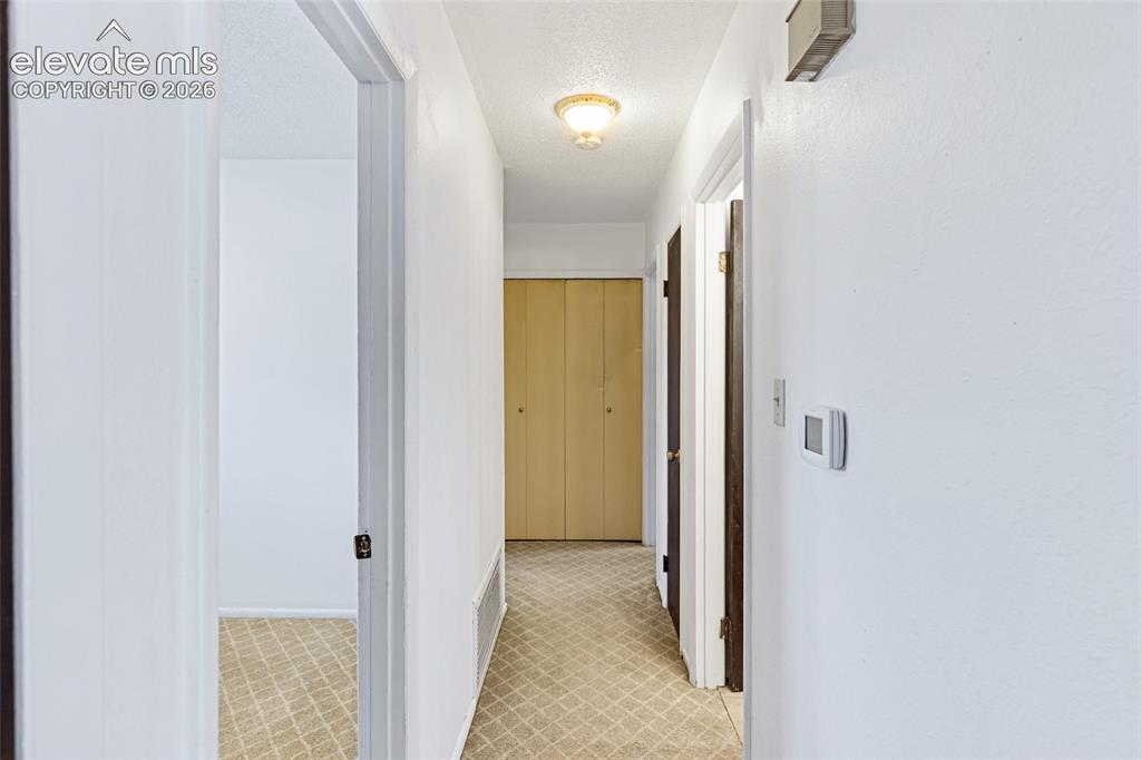 Image 11 of 20: Bright hallway featuring clean white walls, neutral tile flooring with geom