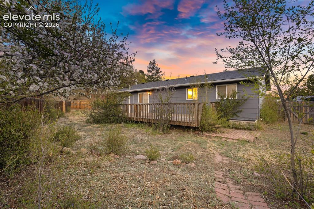 Image 18 of 20: Rear exterior featuring a wooden deck, sliding glass doors, and a brick pat