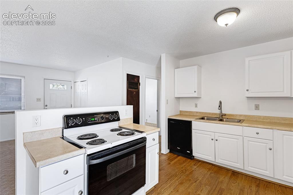 Image 9 of 20: Kitchen featuring white cabinetry, light countertops, wood-finish flooring,