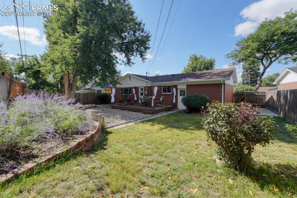 Image 32 of 47: Back of property featuring a fenced backyard, a deck, and brick siding