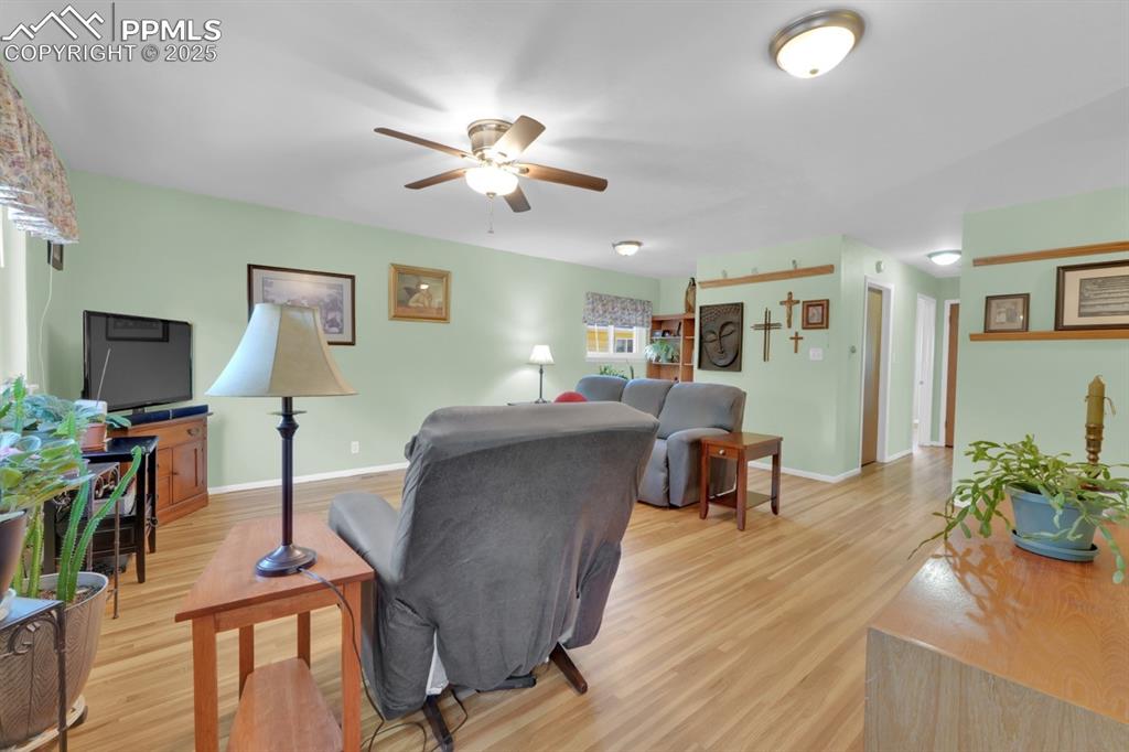 Image 8 of 47: Living room with light wood finished floors and ceiling fan