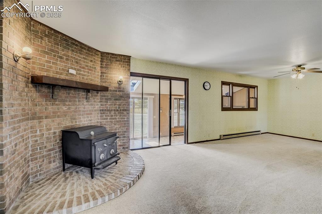 Image 18 of 43: Wood burning fireplace and sliding glass door to the sunroom
